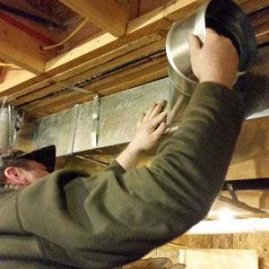 technician installing a whole-house air cleaner beside a furnace in old chatham ny