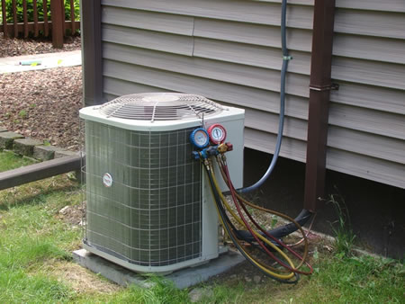 Technician inspecting outdoor AC condenser coil during tune-up in Old Chatham NY